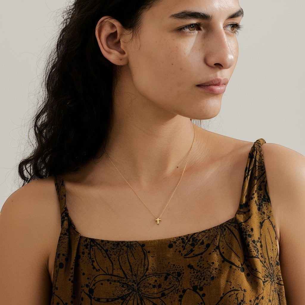 PRO RAY delicate gold cross pendant necklace on a thin chain, worn by a woman.