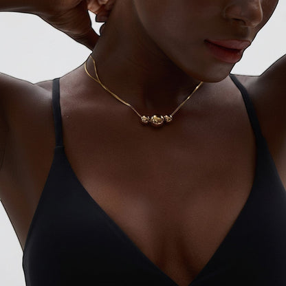 PRO RAY gold NOVA necklace with three graduated spheres on a delicate snake chain, worn by a model.
