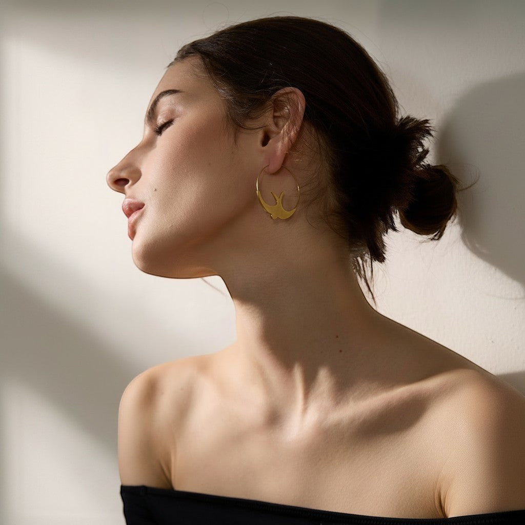 PRO RAY gold hoop earrings with sculptural swallow silhouette, 44mm diameter.