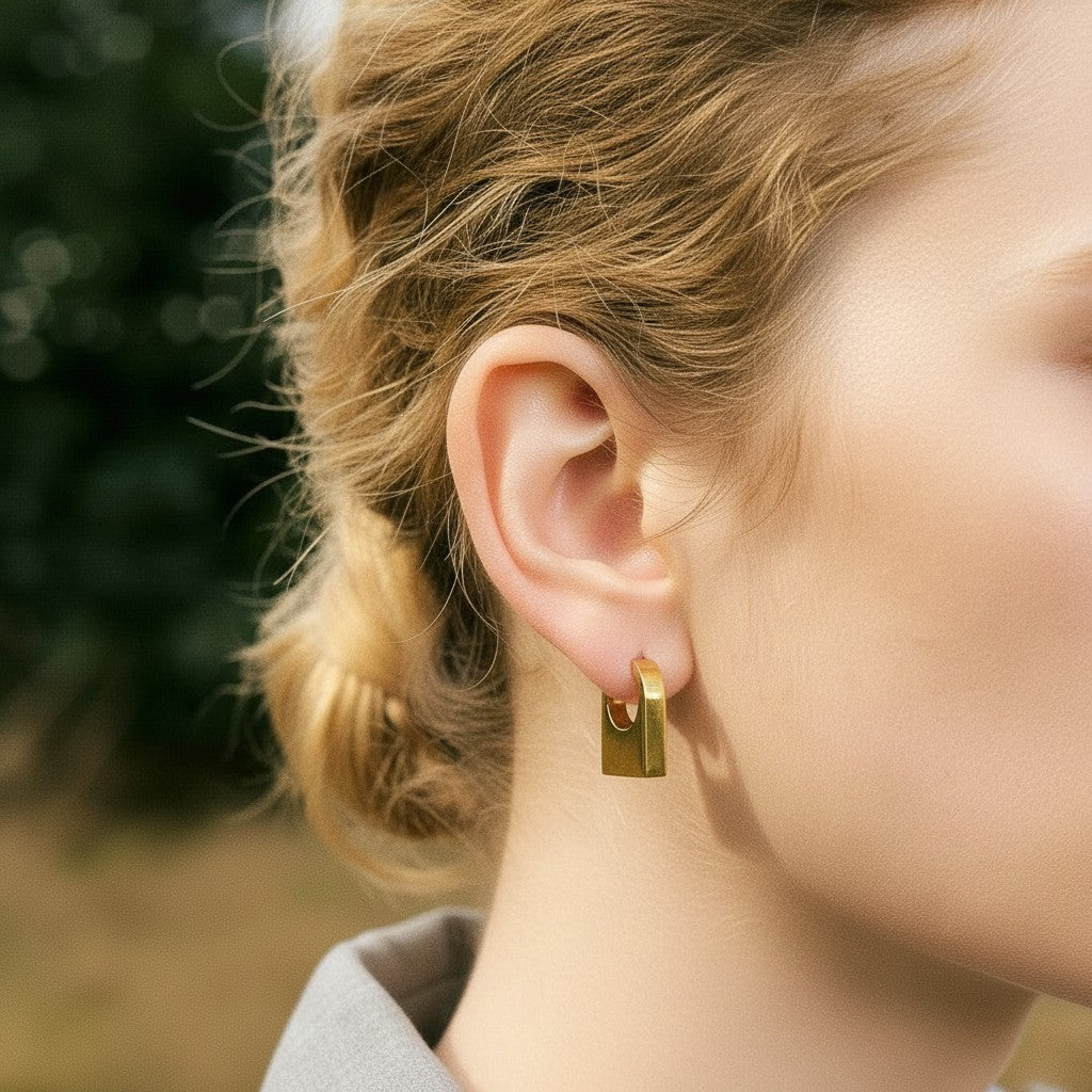PRO RAY KAIA sculptural rectangular gold hoop earrings with a polished finish, worn by a model.