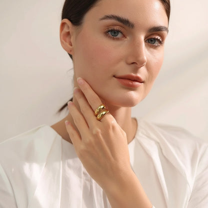PRO RAY SERAVIA Ring: A bold, sculptural gold-tone ring with flowing curved lines and a smooth polished finish. Open silhouette.