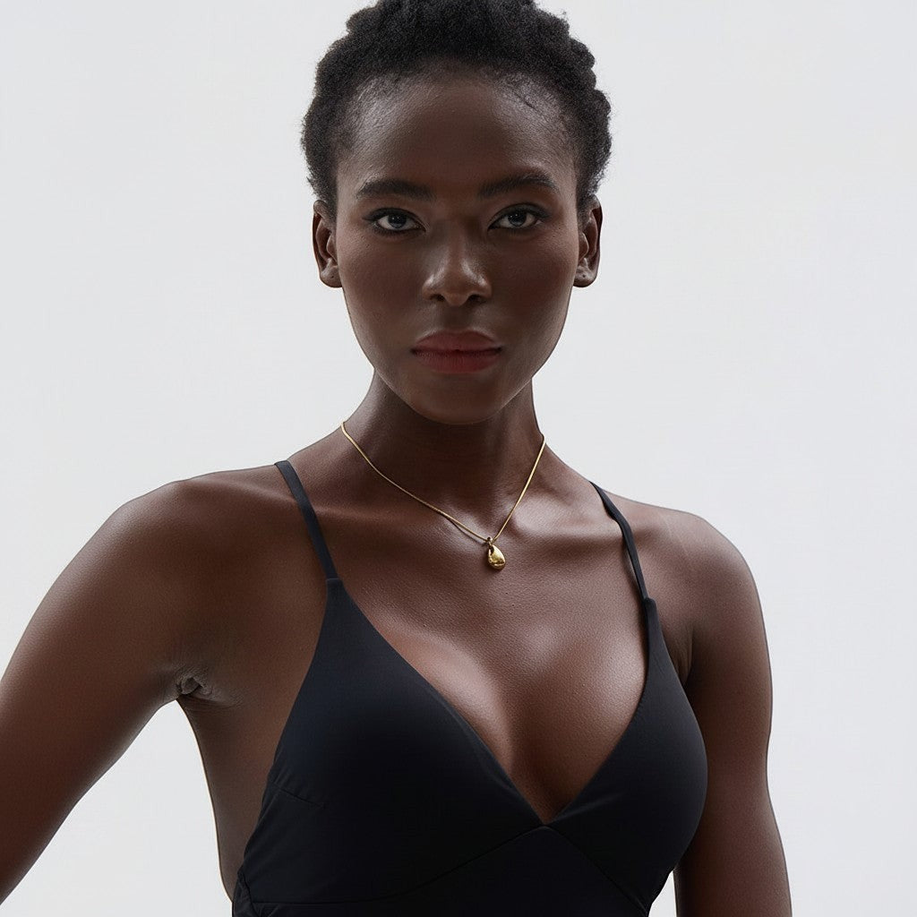 PRO RAY TELYA sculptural gold pendant necklace with soft curves on a thin chain, worn by a model.