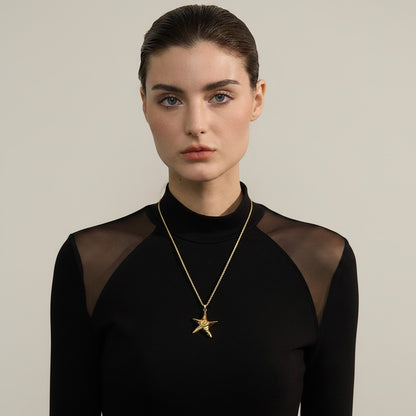 PRO RAY ZOREYA gold star pendant necklace with sculptural detailing on a rope chain, worn by a model.